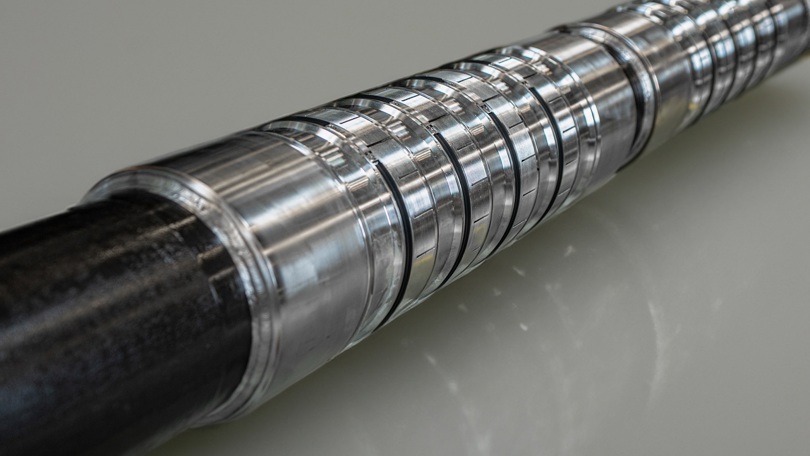Close-up of a Welltec expandable metal annular barrier (WAB) showing precision grooves on a reflective surface.