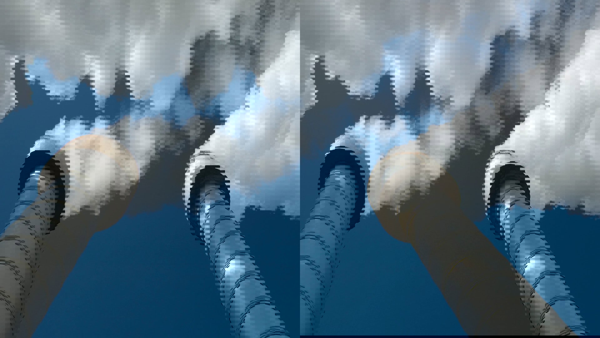 Two industrial chimneys emit white smoke under a blue sky representing high temperature geothermal energy for power generation.